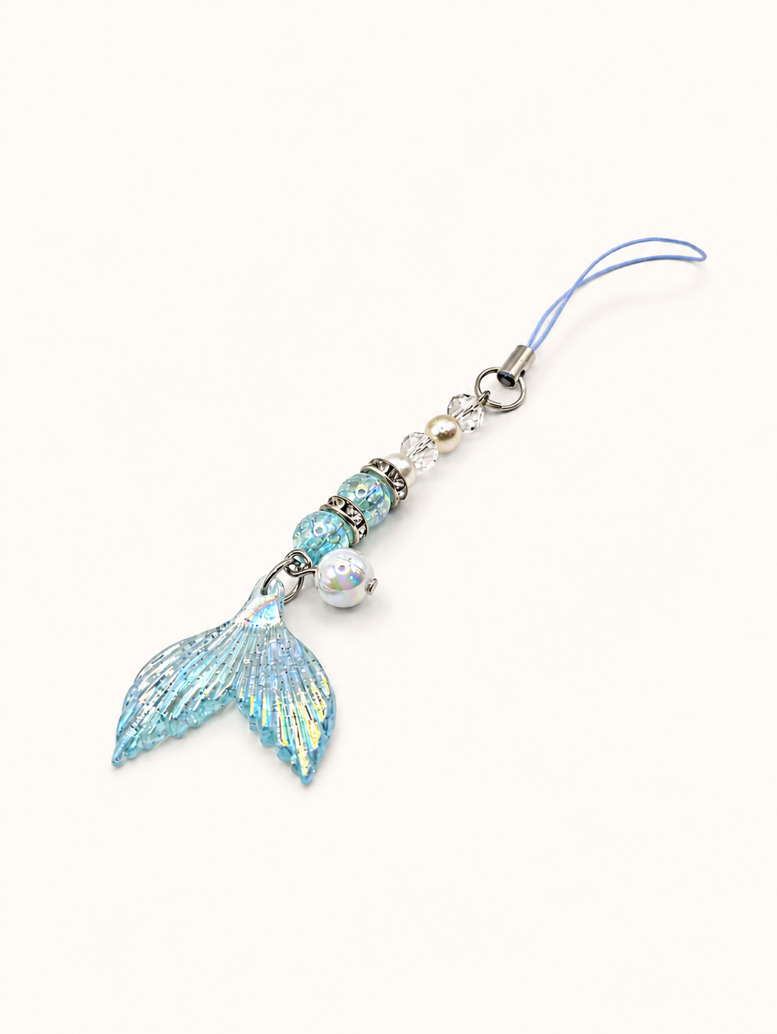 A light blue mermaid tail charm with iridescent glitter, silver beads, and a small pearl bead on a light blue cord, shown on a plain off-white background.